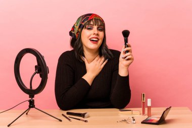 Makyaj sanatçısı, pembe arka planda özel bir makyaj dersi veriyor..