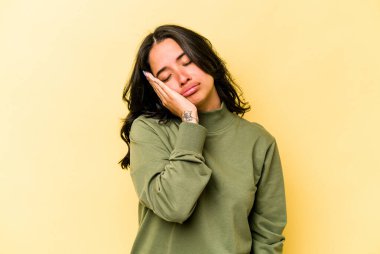 Sarı arka planda izole edilmiş genç İspanyol kadın. Sıkılmış, yorgun ve dinlenmeye ihtiyacı var..