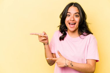 Sarı arka planda izole edilmiş genç İspanyol kadın işaret parmağıyla işaret ettiği için heyecanlı..