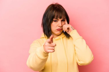 Pembe arka planda izole edilmiş beyaz bir kadın şakağı parmağıyla işaret ediyor, düşünüyor ve bir göreve odaklanıyor..