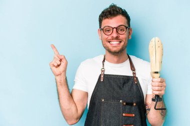 Kafkasyalı genç kunduracı mavi arka planda izole edilmiş gülümseyen ve işaret eden boş alanda bir şey gösteriyor..