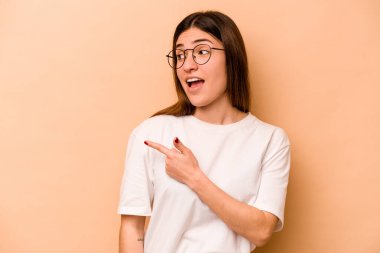 Bej arka planda izole edilmiş genç İspanyol kadın gülümseyen, neşeli ve keyifli görünüyor..