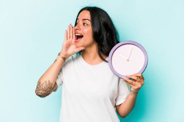 Mavi arka planda izole edilmiş bir saat tutan genç İspanyol kadın bağırıyor ve avuç içini açık tutuyordu..