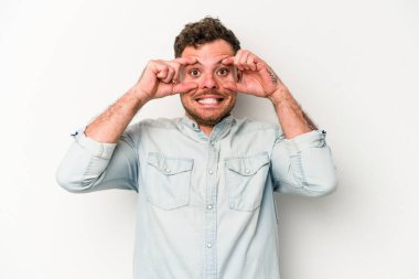 Beyaz arka planda izole edilmiş genç beyaz bir adam bir başarı fırsatı bulmak için gözlerini açık tutuyor..