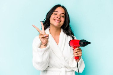 Elinde kurutucu tutan genç İspanyol kadın mavi arka planda iki numarayı parmaklarıyla gösteriyor..