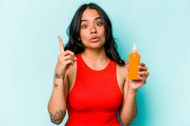 Mavi arka planda güneş kremi tutan genç İspanyol kadının bir fikri var, ilham verici bir kavram..