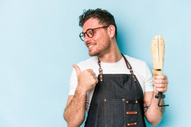 Kafkas ayakkabıcı genç adam mavi arka planda izole parmak uzakta, gülüyor ve kaygısız.