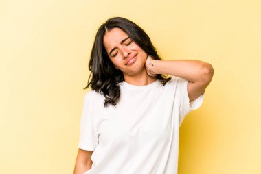 Genç İspanyol kadın sarı arka planda izole edilmiş, dirsek masajı yapıyor, kötü bir hareketin ardından acı çekiyor..