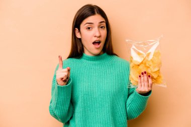 Latin kökenli genç bir kadın, elinde bej arka planda izole edilmiş bir çanta dolusu fiş tutuyor. Bir fikri var, ilham verici bir kavram..