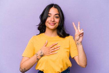 Mor arka planda izole edilmiş genç İspanyol kadın yemin ediyor, elini göğsüne koyuyor..