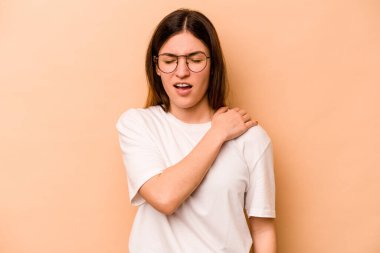 Bej arka planda izole edilmiş genç İspanyol kadın omuz ağrısı çekiyor..