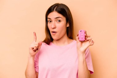 Latin kökenli genç bir kadın bej arka planda izole edilmiş bir araba tutuyor. Bir fikri var, ilham verici bir kavram..