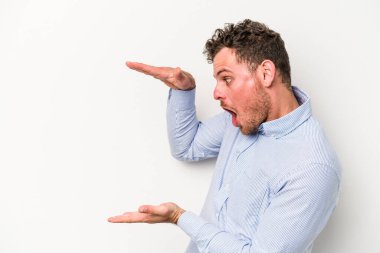 Beyaz arka planda izole edilmiş genç beyaz adam elleri arasında bir kopya alanı tutarken şok ve hayrete düştü..