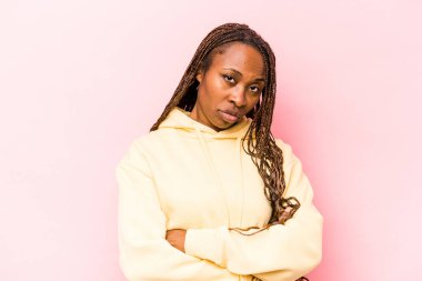 Pembe arka planda izole edilmiş, sıkılmış, yorgun ve dinlenmeye ihtiyacı olan genç Afrikalı Amerikalı kadın..