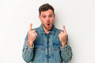 Beyaz arka planda izole edilmiş genç beyaz adam ağzı açık bir şekilde üst tarafı işaret ediyor..