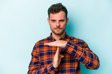 Mavi arka planda izole edilmiş genç beyaz bir adam bir mola hareketi gösteriyor..