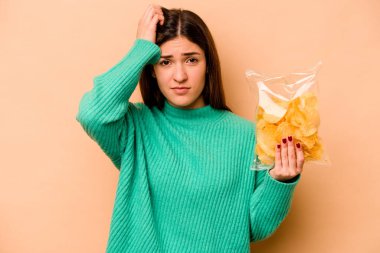 Bej arka planda izole edilmiş bir paket cipsi tutan genç İspanyol kadın şok geçiriyordu. Önemli bir toplantıyı hatırladı..