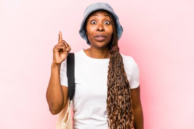 Genç Afrikalı Amerikalı bir kadın pembe arka planda izole plaja gidiyor. Bir fikri var, ilham verici bir kavram..