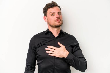 Beyaz arka planda izole edilmiş genç beyaz adam yemin ediyor, elini göğsüne koyuyor..