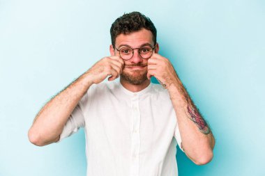 Kafkasyalı genç adam mavi arka planda izole edilmiş iki seçenek arasında şüphe duyuyor.