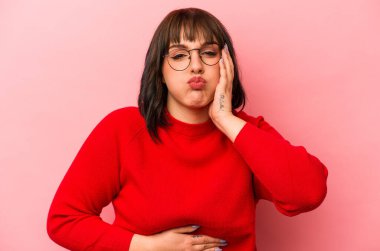 Pembe arka planda izole edilmiş genç beyaz kadın yanakları patlatıyor, yorgun bir ifade takınıyor. Yüz ifadesi kavramı.