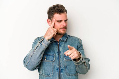 Beyaz arka planda izole edilmiş genç beyaz bir adam şakağı parmağıyla işaret ediyor, düşünüyor ve bir göreve odaklanıyor..