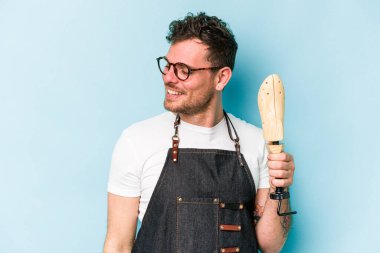 Kafkasyalı genç kunduracı, mavi arka planda izole edilmiş. Gülümsüyor, neşeli ve keyifli..