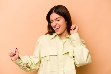 Genç İspanyol kadın bej arka planda izole edilmiş dans ediyor ve eğleniyor..