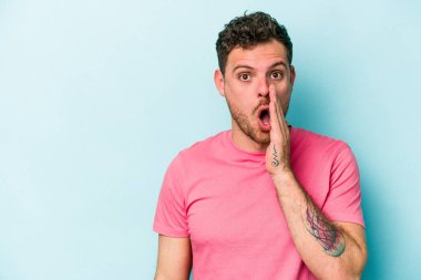 Mavi arka planda izole edilmiş genç beyaz bir adam gizli bir sıcak fren haberi veriyor ve yana bakıyor.