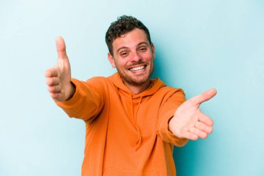 Mavi arka planda izole edilmiş genç beyaz adam kameraya sarıldığı için kendinden emin hissediyor..