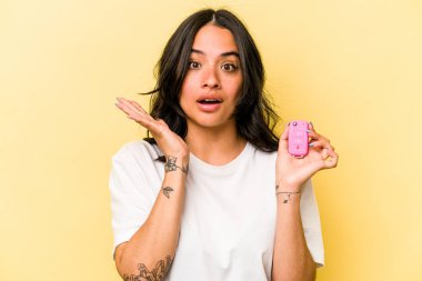Pembe arka planda izole edilmiş anahtar taşıyan genç İspanyol kadın şaşırdı ve şok oldu..