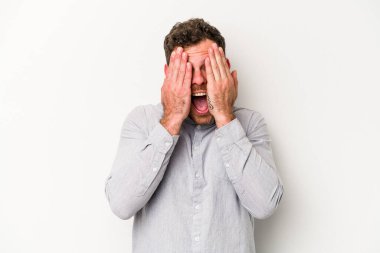 Beyaz arka planda izole edilmiş genç beyaz bir adam yüzünün yarısını palmiye ile örterek eğleniyor..