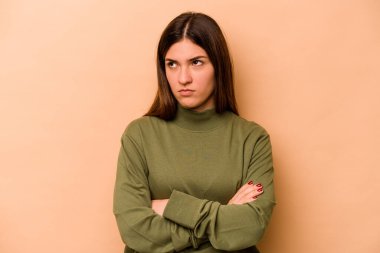 Latin kökenli genç bir kadın bej arka planda izole edilmiş. Tekrarlanan bir görevden yorulmuş..