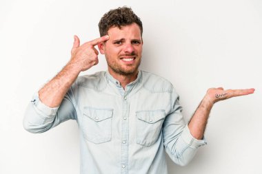 Beyaz arka planda izole edilmiş genç beyaz bir adam elinde bir ürün tutuyor ve.