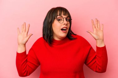 Pembe arka planda izole edilmiş genç beyaz kadın yakın bir tehlike nedeniyle şoka uğruyor.