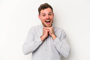 Beyaz arka planda izole edilmiş genç beyaz bir adam şans için dua ediyor, şaşırmış ve ağzını açıp önüne bakıyor..