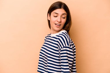 Bej arka planda izole edilmiş genç İspanyol kadın gülümseyen, neşeli ve keyifli görünüyor..