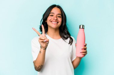 Mavi arka planda termo tutan genç İspanyol kadın iki numarayı parmaklarıyla gösteriyor..