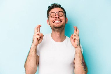 Kafkasyalı genç adam mavi arka planda izole edilmiş şans dilemek için şans diliyor.