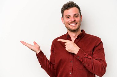 Beyaz arka planda izole edilmiş genç beyaz bir adam, palmiye üzerinde bir fotokopi alanı tutarken heyecanlı..