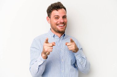 Beyaz arka planda izole edilmiş genç beyaz adam parmaklarıyla ön tarafı işaret ediyor..