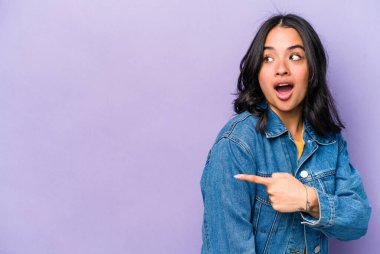 Genç İspanyol kadın mor arka planda izole edilmiş başparmak uzakta, gülüyor ve kaygısız.
