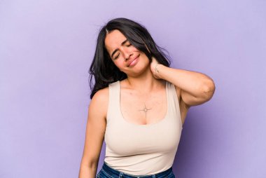 Genç İspanyol kadın, mor arka planda izole edilmiş. Dirsek masajı yapıyor. Kötü bir hareketin ardından acı çekiyor..