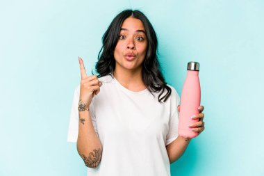 Mavi arka planda termometreyi tutan genç İspanyol kadının harika bir fikri var, yaratıcılık kavramı..