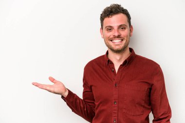 Beyaz arka planda izole edilmiş genç beyaz bir adam bir palmiye üzerinde fotokopi alanı gösteriyor ve belinde başka bir el tutuyor..