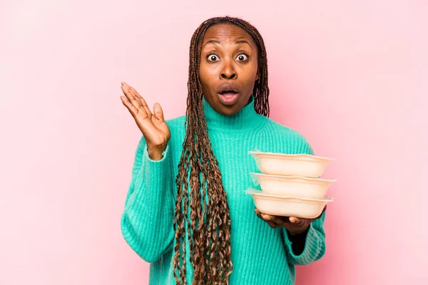 Joven Mujer Afroamericana Sosteniendo Tupperware Aislado Sobre Fondo Rosa Sorprendido —  Fotos de Stock