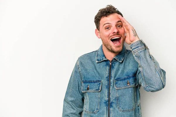 Beyaz arka planda izole genç beyaz adam yüksek sesle bağırıyor, gözleri açık ve elleri gergin tutuyor..