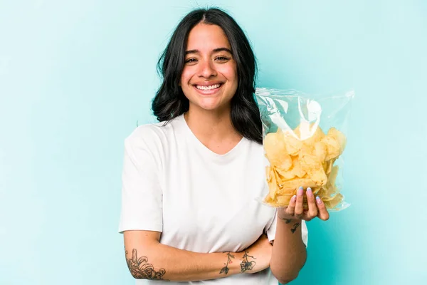 Ung Latinamerikansk Kvinna Håller Påse Chips Isolerad Blå Bakgrund Skrattar — Stockfoto