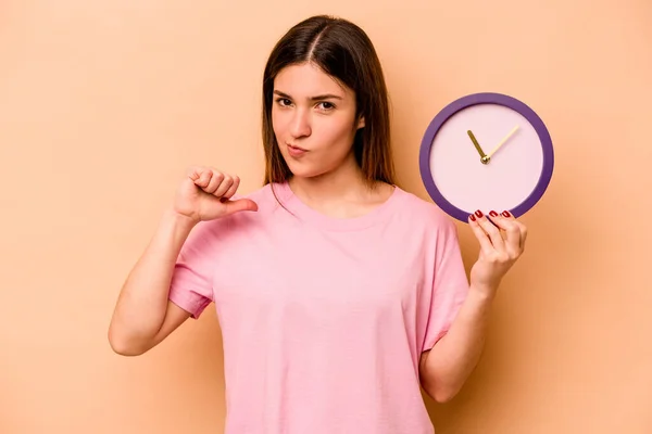 Mujer Hispana Joven Sosteniendo Reloj Aislado Sobre Fondo Beige Siente — Foto de Stock