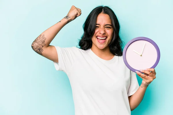 Young Hispanic Woman Holding Clock Isolated Blue Background Raising Fist — Fotografia de Stock